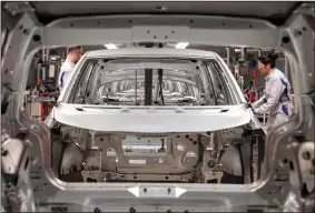  ?? (AP/Jens Meyer) ?? In this February photo, workers complete an electric car ID.3 body at the assembly line during a press tour at the plant of the German manufactur­er Volkswagen AG (VW) in Zwickau, Germany.