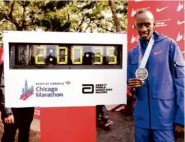  ?? MICHAEL REAVES/GETTY IMAGES ?? Mr. Kiptum posed with his medal and the clock after setting a world record marathon time of 2:00.35 during the Chicago Marathon on Oct. 8, 2023.