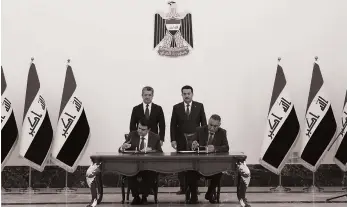  ?? AFP ?? Iraqi Prime Minister Mohammed Shia Al Sudani, back right, and Kurdish leader Masrour Barzani attend the signing of an oil export deal on Tuesday in Baghdad