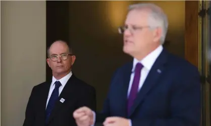  ?? Photograph: Lukas Coch/AAP ?? ‘Confusing rules and a lack of resources undermine people’s capacity to navigate the current crisis.’ Chief medical officer Paul Kelly listens to Scott Morrison speak at a December 2021 Covid press conference.