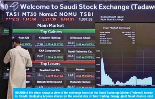  ?? — AFP ?? RIYADH: A file photo shows a view of the exchange board at the Stock Exchange Market (Tadawul) bourse in Riyadh displaying Aramco shares on the second day of their trading. Energy giant Saudi Aramco said yesterday its net profit for the second quarter plunged a massive 73 percent year-on-year due to sharply lower oil prices.