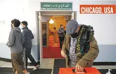  ?? AP ?? CHICAGO, USA
A man makes a donation after taraweeh prayer at Chicago’s Muslim Community Center.