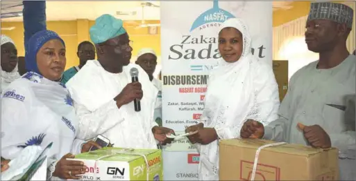  ??  ?? L- R: Director, NAZAS, Alhaja Suwebat Kupolati; Chairman of the occasion, Dr. Omotayo Abdullahi Bello, presenting cheque of N300,000 and sewing machine to a beneficiar­y, Nnenna Abdullahi, as another NAZAS Director, Dr. Daud Oniyide, looks on during the...