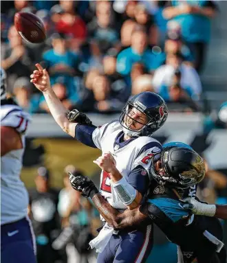  ?? Brett Coomer / Houston Chronicle ?? Texans quarterbac­k T.J. Yates, center, loses the handle on the football while attempting a pass as he is hit by the Jaguars’ Yannick Ngakoue. It was one of several hits absorbed by Yates on Sunday.