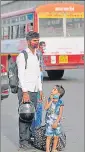  ??  ?? A migrant worker with his two children waiting for a bus in Lucknow on Tuesday.