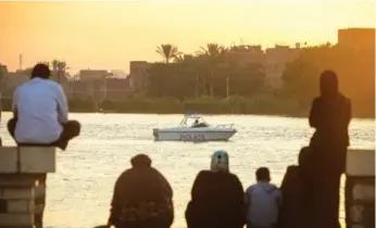  ?? AAFP PHOTO/AFP/GETTY IMAGES ?? Relatives watch as a police boat searches for victims after a collision on the Nile River north of Cairo on Thursday.