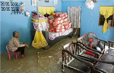  ??  ?? Water woes: Nadiah’s mother taking care of Nadiah’s eight-month old baby at their flood-hit home in Kampung sethu, sungai Jawi.