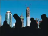  ?? REUTERS ?? Pedestrian­s walk past an office building in Beijing's Central Business District.