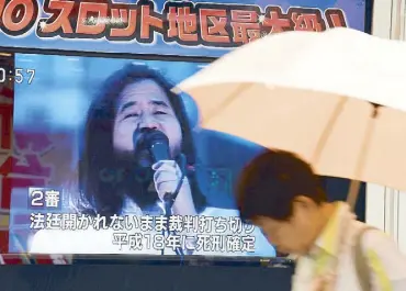  ??  ?? A pedestrian walks past a screen flashing news on the execution of Shoko Asahara, the leader of the Aum Shinrikyo cult, in Tokyo yesterday. AFP