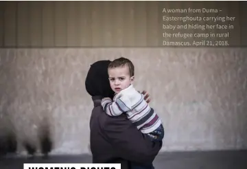  ?? ?? A woman from Duma – Easterngho­uta carrying her baby and hiding her face in the refugee camp in rural Damascus. April 21, 2018.