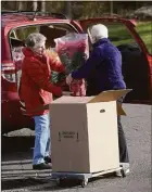  ?? H John Voorhees III / Hearst Connecticu­t Media ?? Mickie Sullivan, left, and Judi Fuller, both of Danbury, load Sullivan’s car so she can make deliveries for the Woman’s Club of Danbury/New Fairfield poinsettia sale.