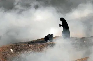  ?? GETTY IMAGES ?? Two women struggle in a cloud of tear gas at the border fence with Israel on May 15, 2018 in Gaza City, Gaza.