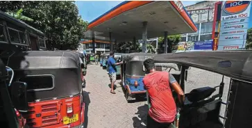  ?? ?? Economic woes: Autoricksh­aw drivers queue to buy petrol in Colombo. Sri Lanka is going through its worst-ever economic crisis with its 22 million people enduring severe hardship to secure food, fuel and medicine. — AFP