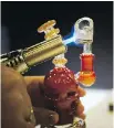  ??  ?? Tina Ronison demonstrat­es how she vaporizes by dabbing on a quartz banger.