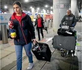  ?? AP ?? Mohammed Hafar, right, helps daughter Jana Hafar with her luggage as they leave JFK Airport in New York. Jana had been forced by President Donald Trump’s travel ban to stay behind in Syria for months while her father, his wife and son Karim started rebuilding their lives in Bloomfield, New Jersey, with no clear idea of when the family would be together again.