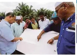  ??  ?? SULAIMAN (kiri) bersama peneroka melihat pelan kawasan ladang ditebang.