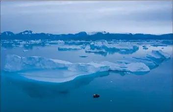  ?? Felipe Dana Associated Press ?? ICE CORE data reveal a sharp increase in Greenland’s temperatur­es since 1995, showing the island 2.7 degrees higher than its 20th century average. Above, a boat navigates next to icebergs near the town of Kulusuk.