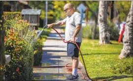  ?? Francine Orr Los Angeles Times ?? SCOTT MOSES waters f lowers in his frontyard in South Pasadena. Many water suppliers are offering rebates for replacing lawns with drought-tolerant gardens.