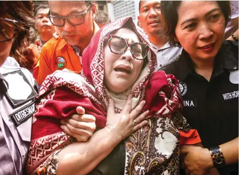  ?? SALMAN TOYIBI/JAWA POS ?? TERUS MENANGIS: Nunung berjalan dibantu polwan disusul suaminya, Iyan Sambiran, setelah rilis kasus di Mapolda Metro Jaya kemarin (22/7).