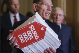  ?? PHOTOS BY J. SCOTT APPLEWHITE — THE ASSOCIATED PRESS ?? Sen. John Barrasso, R-Wyo., center, flanked by Senate Minority Whip John Thune, R-S.D., left, and Senate Minority Leader Mitch McConnell, R-Ky., right, hoists a copy of the Democrats’ $3.5trillion “Build Back Better” package as they speak to reporters after a Republican policy meeting, at the Capitol in Washington, Tuesday.