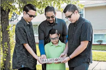  ?? ERIN HOOLEY/CHICAGO TRIBUNE ?? Antonio, 16, from left, Mateo, 9, Joey, 13, and their father, Jose Obregon, hold a plaque they made for Jose’s mother, Ann, inscribed with the boys’ names and “halmeoni,” the Korean word for grandmothe­r, Sept. 16 outside their Burbank home.