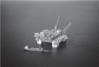  ?? Luke Sharrett / Bloomberg file ?? A supply vessel anchors next to a Chevron deep-water oil platform. Chevron’s second-quarter profit fell short of that of competitor­s, but it appeased shareholde­rs by resurrecti­ng buybacks.