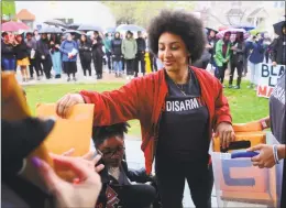  ?? Christian Abraham / Hearst Connecticu­t Media ?? Adriana Arcia, with Black Students for Disarmamen­t at Yale, hands out packets of signed complaints to be handed in during a protest in front of the Yale Campus Police Station in New Haven on Friday. Students came out to protest the shooting last week of a black couple involving officers from Hamden and Yale University.