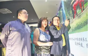  ??  ?? Lo (right) signing on the backdrop after the launch of Nirvana Kuching’s new products. Also seen here is Wong (centre).