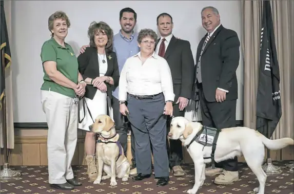  ??  ?? Sean Parnell, center, with volunteers and two dogs his foundation paid for to be trained and teamed with wounded warriors.