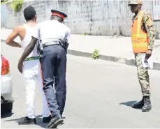  ?? FILE ?? A Jamaica Defence Force soldier looks on as a policeman searches a bypasser for contraband at a checkpoint on Greenwich Park Road in Kingston on September 23, 2018 A state of emergency in force since last year elapsed earlier this month.