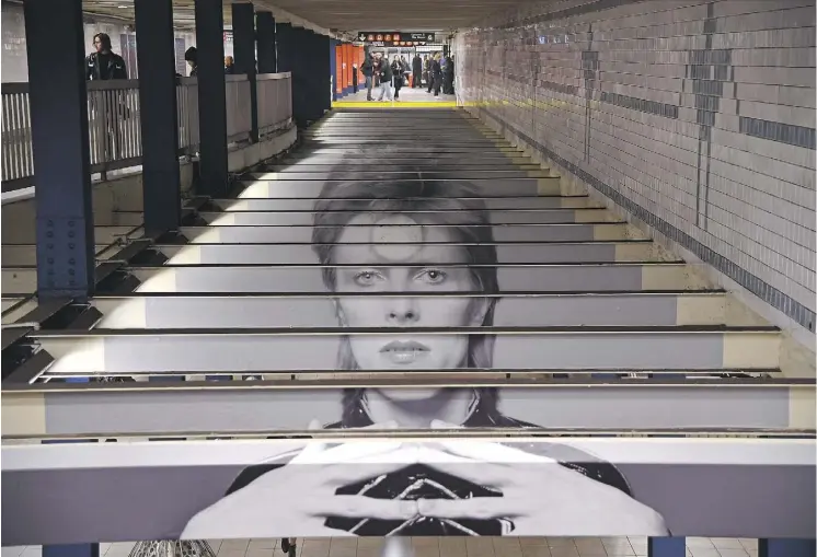  ?? ANGELA WEISS/AFP/GETTY IMAGES ?? A David Bowie art installati­on is seen at the Broadway-Lafayette subway station in New York. The large Bowie-inspired art is in collaborat­ion with Spotify and the Brooklyn Museum’s exhibition David Bowie Is. Bowie was said to ride the train carrying a Greek newspaper to make people think he was a Greek man who resembled the famous singer.