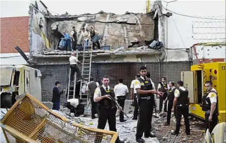  ?? AP/Reuters ?? War zone: Prosegur guards and police inspecting the vault that the robbers blew up in Ciudad del Este. The attackers, armed with assault rifles and explosives, had crossed from Brazil and left a trail of destructio­n, which included shot out and damaged...