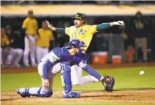  ?? Ezra Shaw / Getty Images ?? Matt Joyce slides past Kansas City’s Drew Butera on Marcus Semien’s single to cap the A’s six-run rally in the eighth.