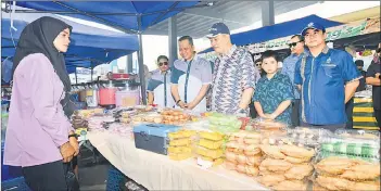  ?? ?? Chief Minister Datuk Seri Panglima Haji Hajiji Haji Noor and his son Mohd Danish visiting the Ramadan Bazaar near CKS Kampung Selupoh.