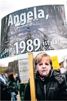  ?? FOTO: ANDREAS BRETZ ?? „Angela, dein 1989 ist da!“, stand auf dem Plakat, das diese Person mit Merkel-Maske Mitte April in Düsseldorf hochhielt.