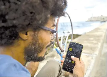  ?? — AFP photos ?? Gonzalez uses his cell phone to connect to the internet at the Malecon in Havana.