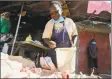  ??  ?? Margaret Awino, 54, who lost her job as a cleaner for a charity, prepares chicken to fry in the street in Nairobi, Kenya.