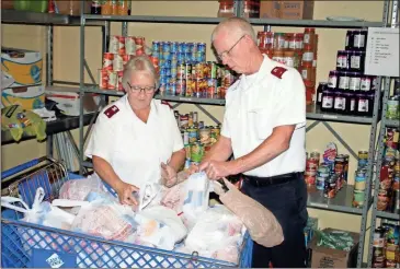  ?? Doug Walker ?? Salvation Army lieutenant­s Paula and Tim Blevins sort through the canned food pantry at the Rome headquarte­rs on East First Avenue, bagging food to give to the needy