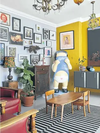  ??  ?? The living room is filled with art and design. The large painting on the yellow wall is Johannes Phokela’s “Ecstasy Of Medusa (Trustafari­an) and the grey server underneath is by Dokter and Misses. Frank van Reenen’s ‘Shy Girl’ stands in the corner.