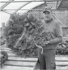  ?? CHRIS CONNNORS/CAPE BRETON POST ?? Kevin Elworthy of Elworthy’s Nature in Bloom Greenhouse shows one of the wreaths he sells at his George Street business.