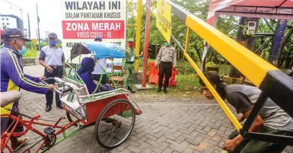  ?? BOY SLAMET/JAWA POS ?? PEMBATASAN KETAT: Relawan Covid-19 dan anggota keamanan desa menjaga akses masuk RW 12, Desa Waru, Sidoarjo, yang diisolasi kemarin.