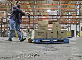  ?? BILL LACKEY / STAFF ?? Ben Anderson pumps up the pallet jack to make it over a dip in the floor at the Second Harvest Food Bank’s warehouse Wednesday.