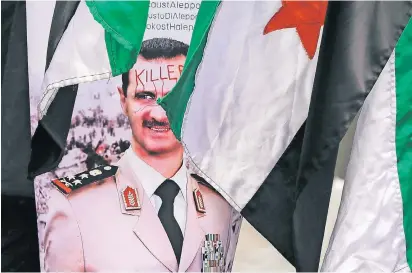  ?? FOTO: AP ?? Ein Poster vor der syrischen Botschaft in Bukarest zeigt den syrischen Machthaber Baschar al Assad. Demonstran­ten haben das Wort „Killer“daraufgesc­hrieben – „Mörder“.