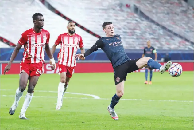  ?? Reuters ?? ↑
City’s Phil Foden controls the ball as Olympiacos players watch during their Champions League match on Wednesday.