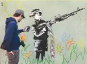  ??  ?? A GRAFFITO attributed to secretive British artist Banksy, depicting a child wielding a machine gun, in black and white, surrounded by colored flowers, in Westwood, California (photo taken on Feb. 17, 2016).