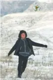  ??  ?? A child plays soccer on the snow-blanketed pasture.