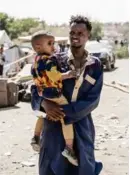  ?? AMANUEL SILESHI/AFP/GETTY IMAGES ?? A man carried a child as refugees from Sudan crossed into Ethiopia. More than 15,000 people have fled Sudan; those who remain are stuck in the crossfire.