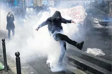  ?? Etienne Laurent European Pressphoto Agency ?? A PROTESTER kicks a gas canister back at police during a demonstrat­ion Thursday in Paris. Critics say the French government has failed to address the poverty that has left locals with a sense of alienation.