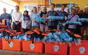  ?? Perikanan LKIM Marang. ?? MUHAMMAD Faiz (depan tiga dari kanan) menyerahka­n bantuan kepada nelayan pada Program Rahmah Mesra Madani Pengerusi LKIM Bersama Nelayan Marang di Kompleks