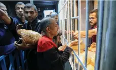  ?? AFP ?? Above, displaced Palestinia­ns buy bread from a bakery in Gaza city; right, fruit stalls at Al Nuseirat refugee camp